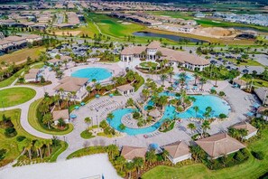 Vista aérea de un complejo turístico con dos piscinas grandes, un campo de golf y varios edificios.