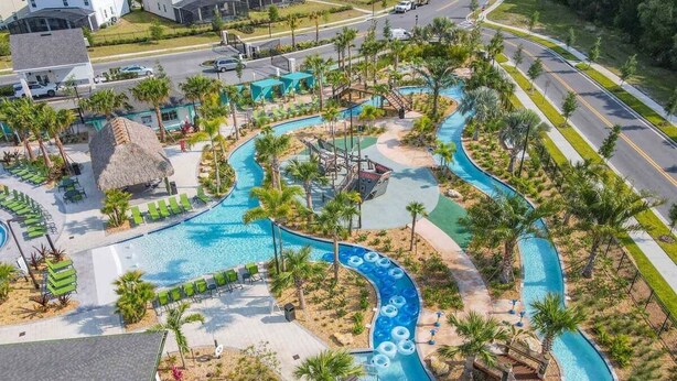An aerial view of a resort with a winding pool, lounge areas, and palm trees. - Last Minute Disney Getaway! Luxury Condo with Private Balcony. Book Now! #87985 (Orlando)