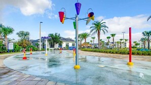 A water feature with colorful buckets and a fountain in a plaza with palm trees and buildings in the background. - Last Minute Disney Getaway! Luxury Condo with Private Balcony. Book Now! #87985 (Orlando)