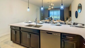 A modern kitchen with a central island, built-in appliances, and pendant lighting. - Last Minute Disney Getaway! Themed Bedrooms & Private Balcony. Book Now! #87993 (Orlando)