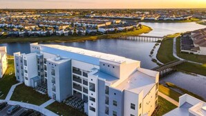 A modern multi-story building with a flat roof, large windows, and a parking lot. - Last Minute Disney Getaway! Luxury Condo with Private Balcony. Book Now! #88007 (Orlando)