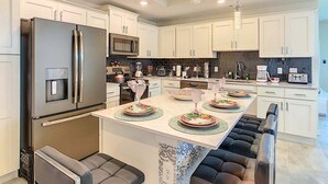 A modern kitchen with white cabinets, stainless steel appliances, and a central island with seating. - Last Minute Disney Getaway! Luxury Condo with Private Balcony. Book Now! #88007 (Orlando)