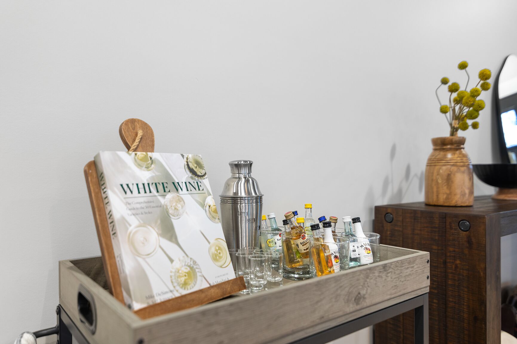 A tray with a white wine bottle, a cocktail shaker, and various liquor bottles.