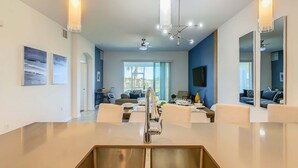 Een moderne keuken met een centraal eiland, een roestvrijstalen spoelbak en hanglampen.