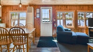 A wooden cabin interior with a dining area, a sofa, and a television. - Bayview Resort Waters Edge Cabin 2 (Saint Germain)