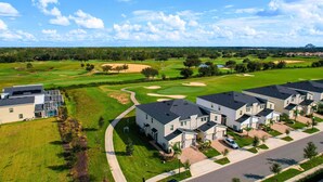 Un quartier résidentiel avec des maisons modernes, un terrain de golf et un grand bâtiment doté d’une façade en verre.