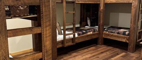 A room with bunk beds, wooden flooring, and a ceiling fan.