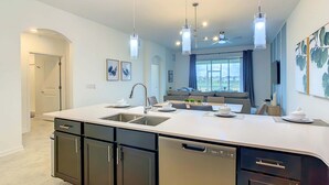 A modern kitchen with a central island, built-in dishwasher, and pendant lighting. - Last Minute Disney Getaway! Luxury Condo with Private Balcony. Book Now! #88067 (Orlando)