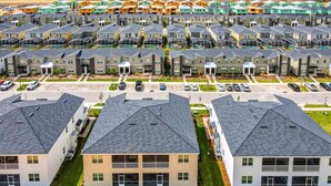 A residential area with multiple townhouses, each with a garage and a small front yard. - Last Minute Disney Getaway! Luxury Condo with Private Balcony. Book Now! #88067 (Orlando)