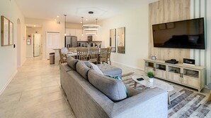 Ein modernes Wohnzimmer mit einer großen Couch, einem Essbereich und einer Küche im Hintergrund.