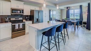 A modern kitchen with white cabinets, stainless steel appliances, and a central island with bar stools.