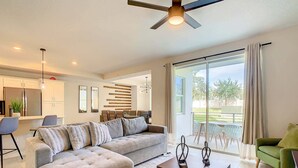 A modern living room with a sectional sofa, a coffee table, and a dining area with chairs and a table. - Last Minute Disney Getaway! Luxury Condo with Private Balcony. Book Now! #88109 (Orlando)