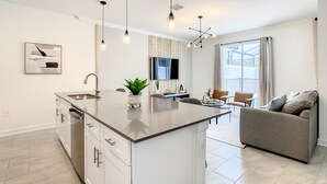Una cocina moderna con una isla central, electrodomésticos de acero inoxidable e iluminación colgante.