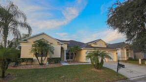 A residential house with a front yard, palm trees, and a mailbox.