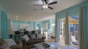 A spacious living room with a ceiling fan, a glass coffee table, and a sofa.