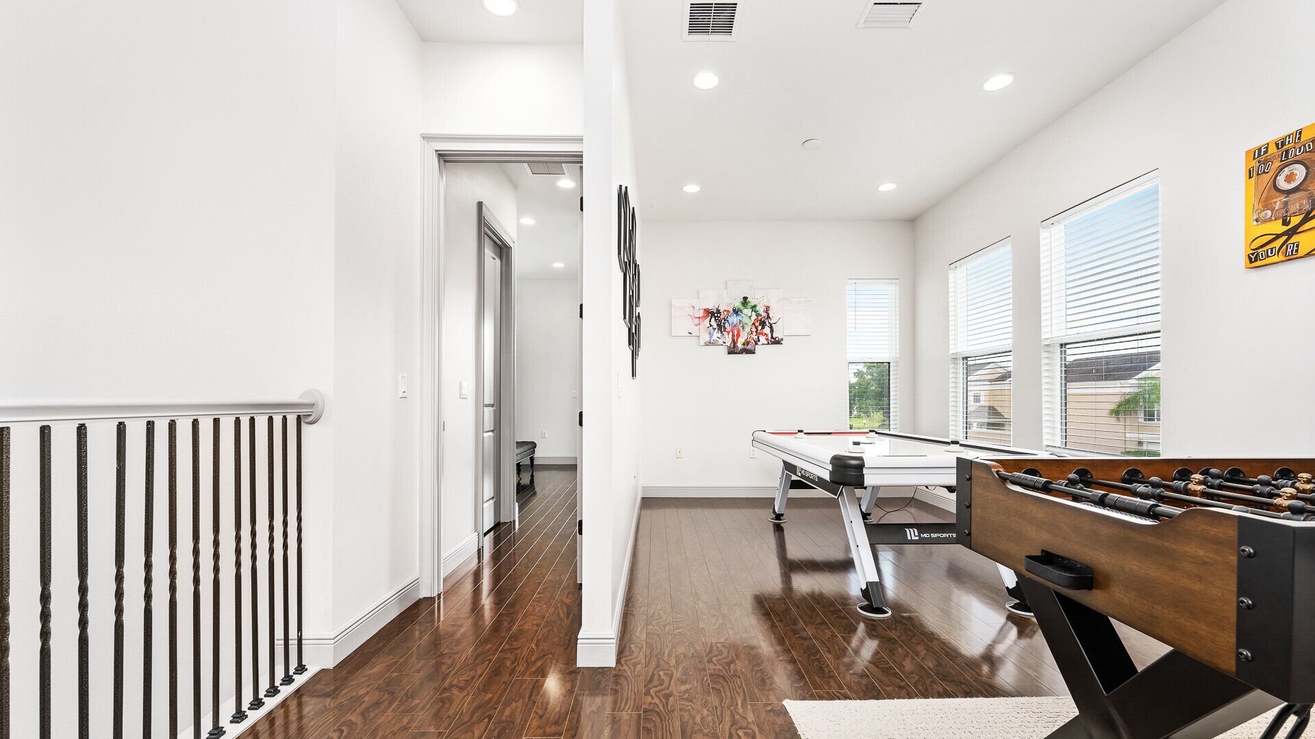 A spacious room with a pool table, a foosball table, and a door leading to another area.