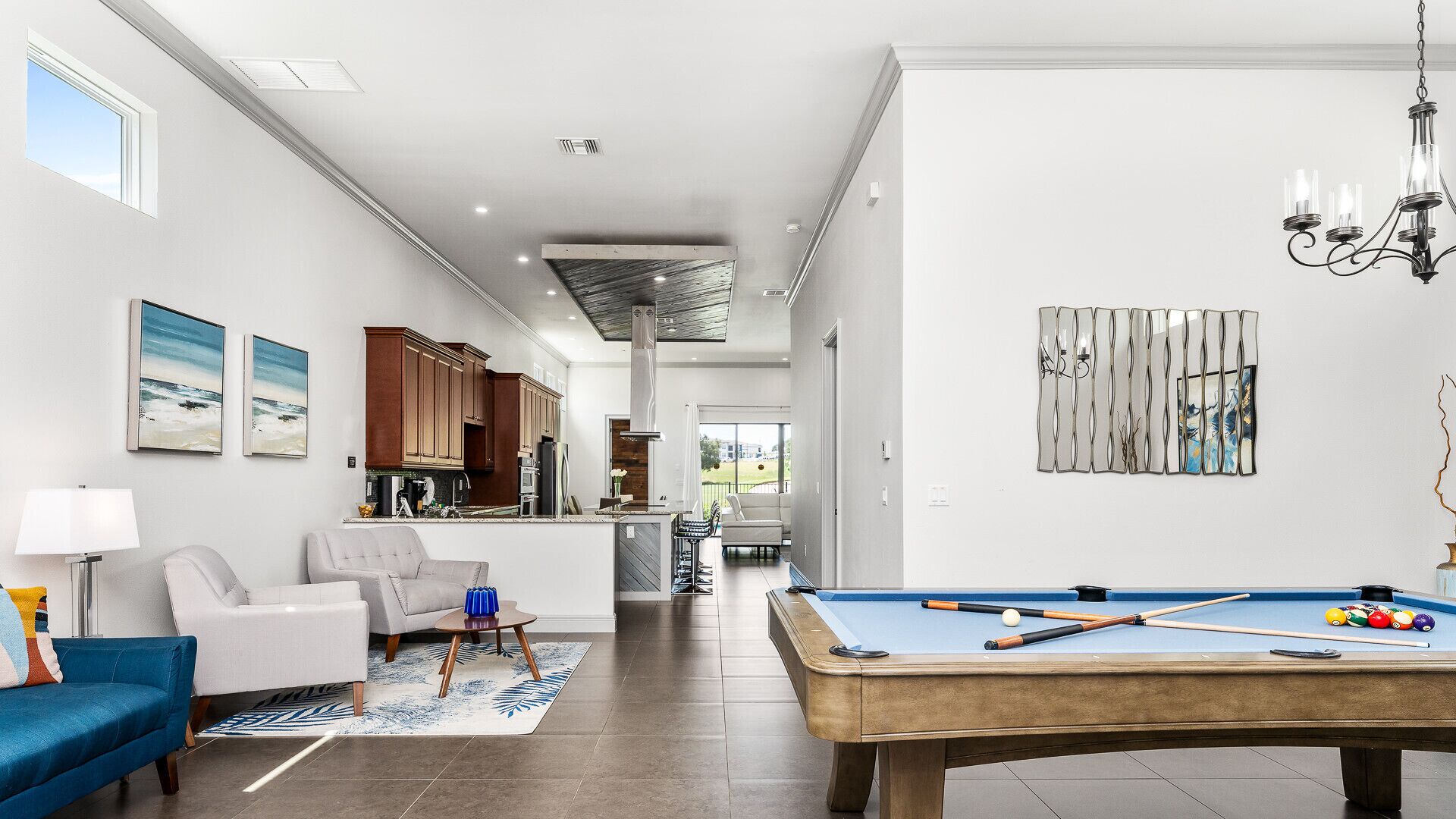 Een moderne woonkamer met een pooltafel, een bank en een eethoek met houten kasten.
