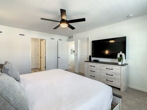 A bedroom with a bed, a ceiling fan, a dresser, a TV, and a door leading to another room. - Last Minute Disney Getaway! Private Pool & Themed Bedrooms. Book Now! #100093 (Orlando)