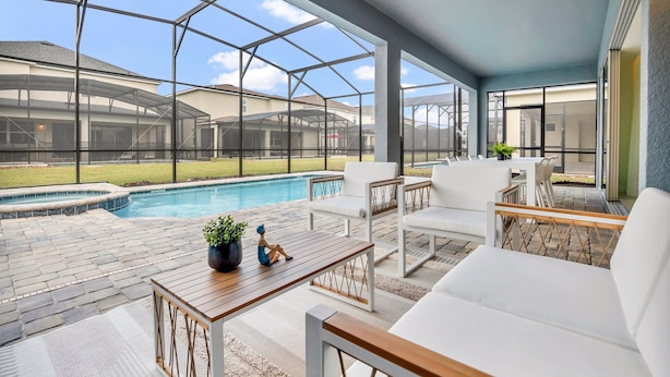 Eine überdachte Terrasse mit Pool, Gartenmöbeln und Blick auf den Garten.