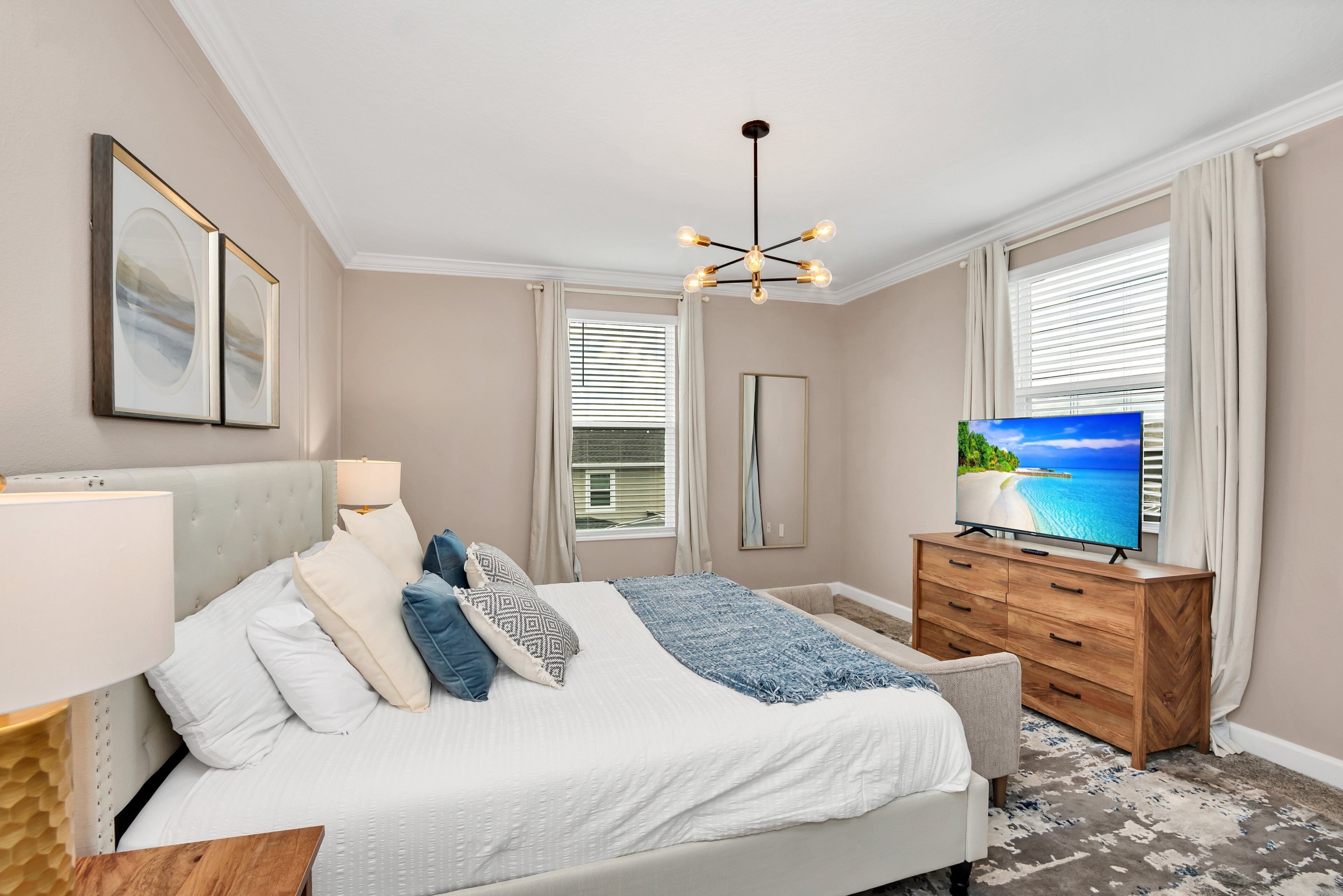 Ein Schlafzimmer mit einem Bett, einem Fernseher, einer Kommode und einem Fenster mit Jalousien.