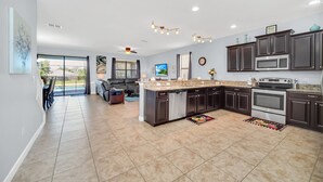 A spacious kitchen with dark cabinetry, a central island, and a large window. - Last Minute Disney! Private Pool, Game Room & Themed Bedrooms. Book Now! #60021 (Orlando)
