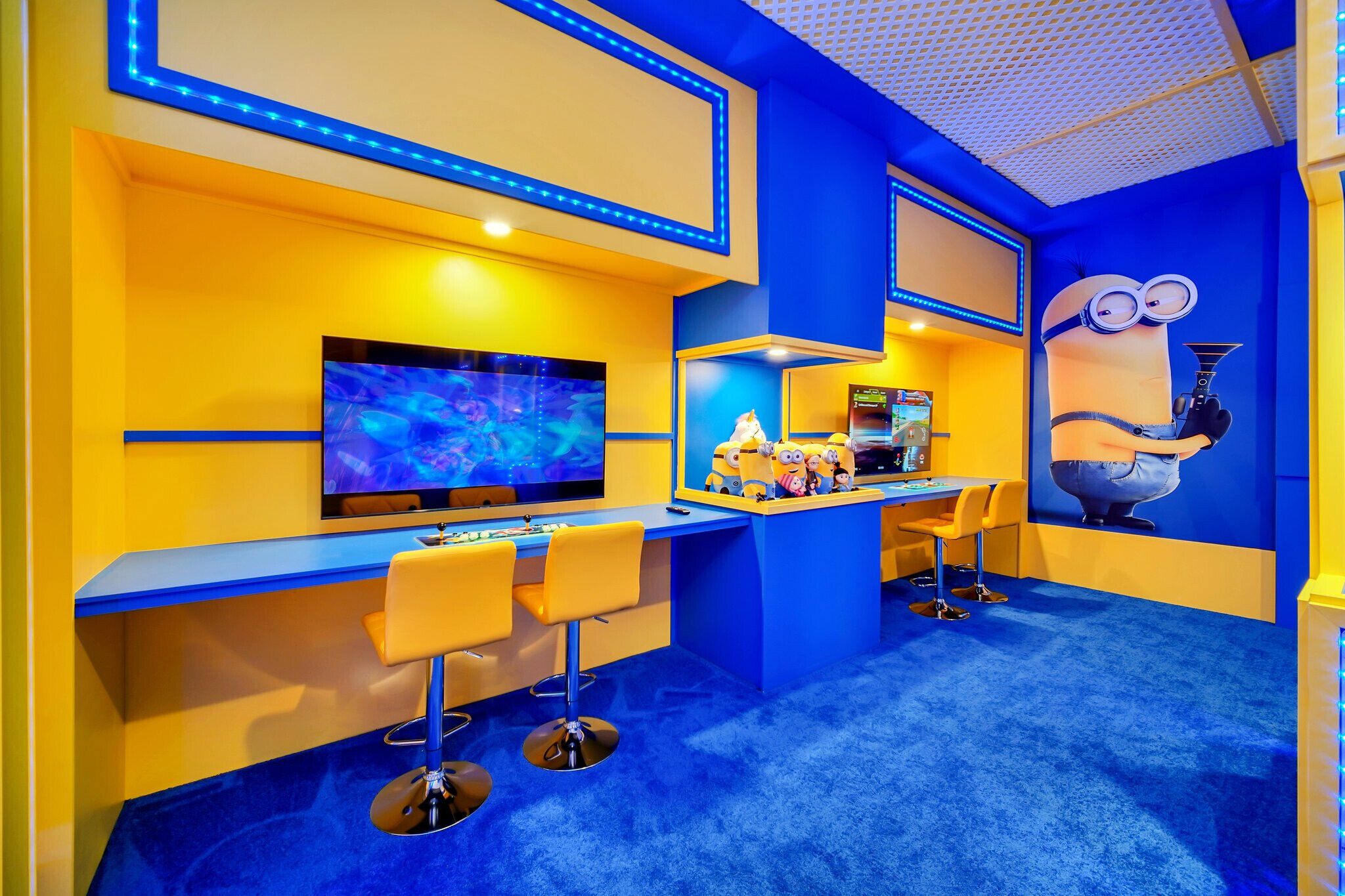 A vibrant room with a large screen, bar area, and playful decor including a Minion character.