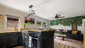 Eine moderne Küche mit einer zentralen Kochinsel, integriertem Backofen und einer Essecke mit Sofa und Couchtisch.
