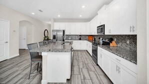 A modern kitchen with white cabinets, granite countertops, and a central island.