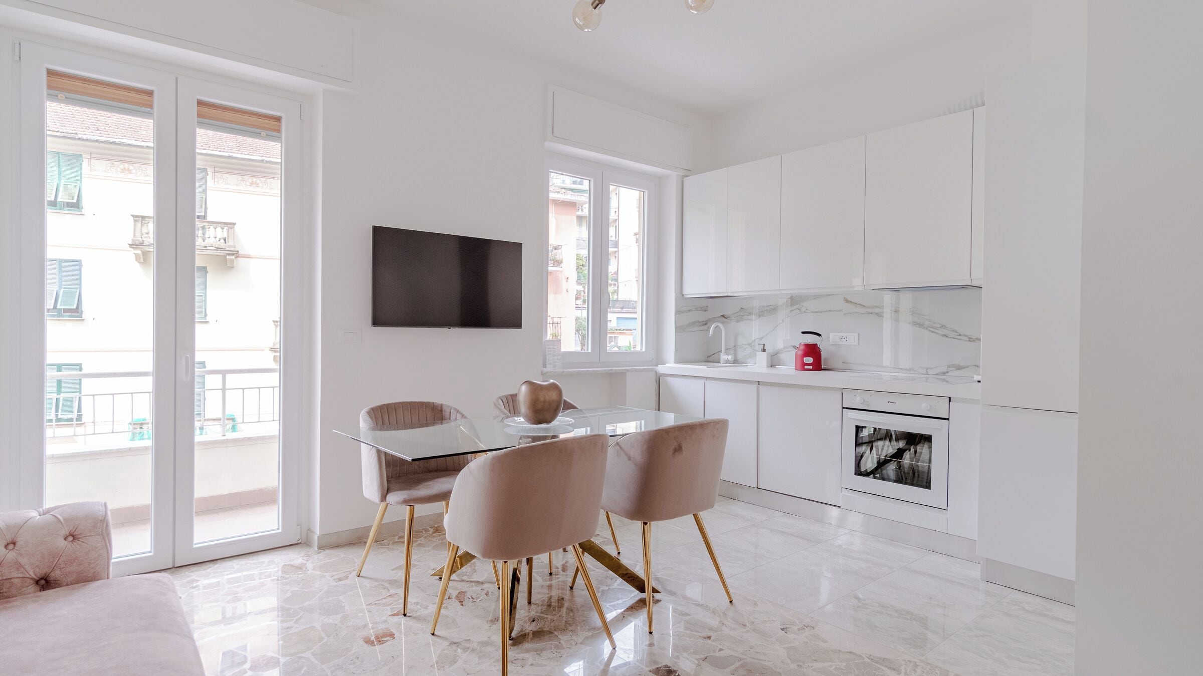 Una cocina moderna con armarios blancos, encimera de mármol y horno empotrado.