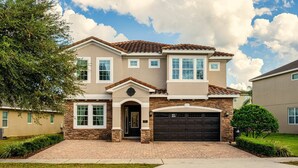 Une maison à deux étages avec une façade en briques, une porte de garage marron foncé et une pelouse bien entretenue.