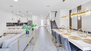 Una cocina moderna con una isla central, taburetes de bar e iluminación colgante.