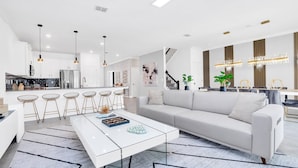 Una cocina moderna con armarios blancos, una isla central e iluminación colgante.