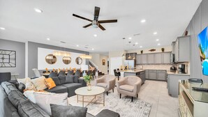 A modern living room with a grey sectional sofa, a round coffee table, and a ceiling fan. - Last Minute Disney! Private Pool, Hot Tub, Game Room & Themed Bedrooms. Book Now! #78231 (Orlando)