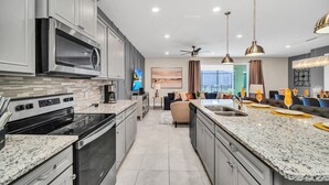 A modern kitchen with granite countertops, stainless steel appliances, and a central island with a sink. - Last Minute Disney! Private Pool, Hot Tub, Game Room & Themed Bedrooms. Book Now! #78231 (Orlando)