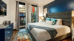 Un dormitorio moderno con una cama grande, un ventilador de techo y vistas a un edificio a través de una puerta de vidrio.