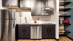 Una cocina moderna con electrodomésticos de acero inoxidable, armarios oscuros y un microondas sobre la encimera.