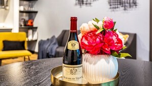 Une bouteille de vin Beaujolais-Villages millésimé 2022, posée sur un plateau, à côté d’un vase rempli de fleurs.