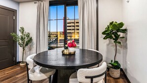 Un coin repas avec une table ronde, deux chaises, un vase avec des fleurs et une bouteille.