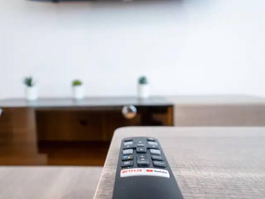 A remote control with Netflix and YouTube logos on a wooden surface.