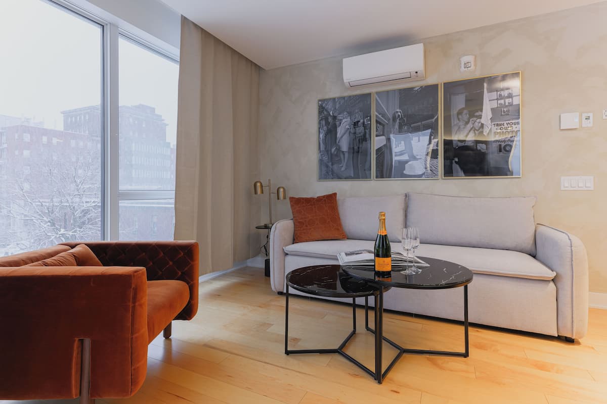 Un salon moderne avec un canapé, une table basse et une grande fenêtre donnant sur la ville.