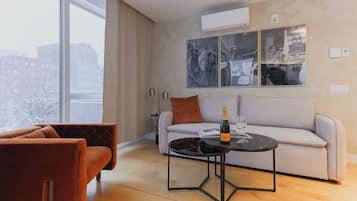 Ein modernes Wohnzimmer mit einer Couch, einem Couchtisch und einem großen Fenster mit Blick auf die Stadt.