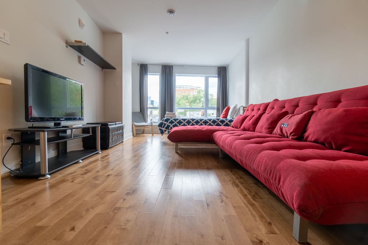 Un salon moderne avec un canapé rouge, un téléviseur à écran plat et un plancher en bois.