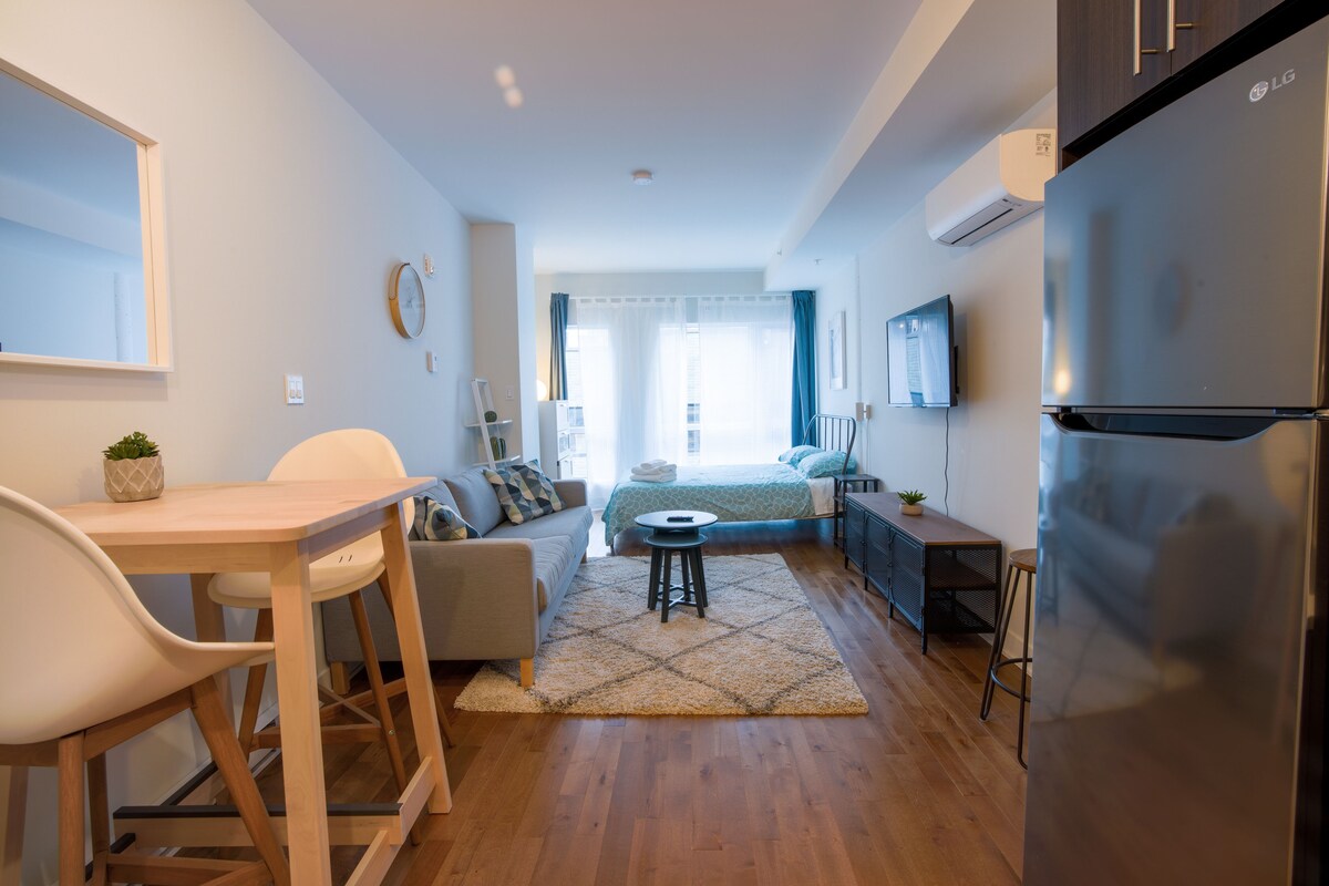 A compact living space with a kitchenette, a dining area, and a bedroom.