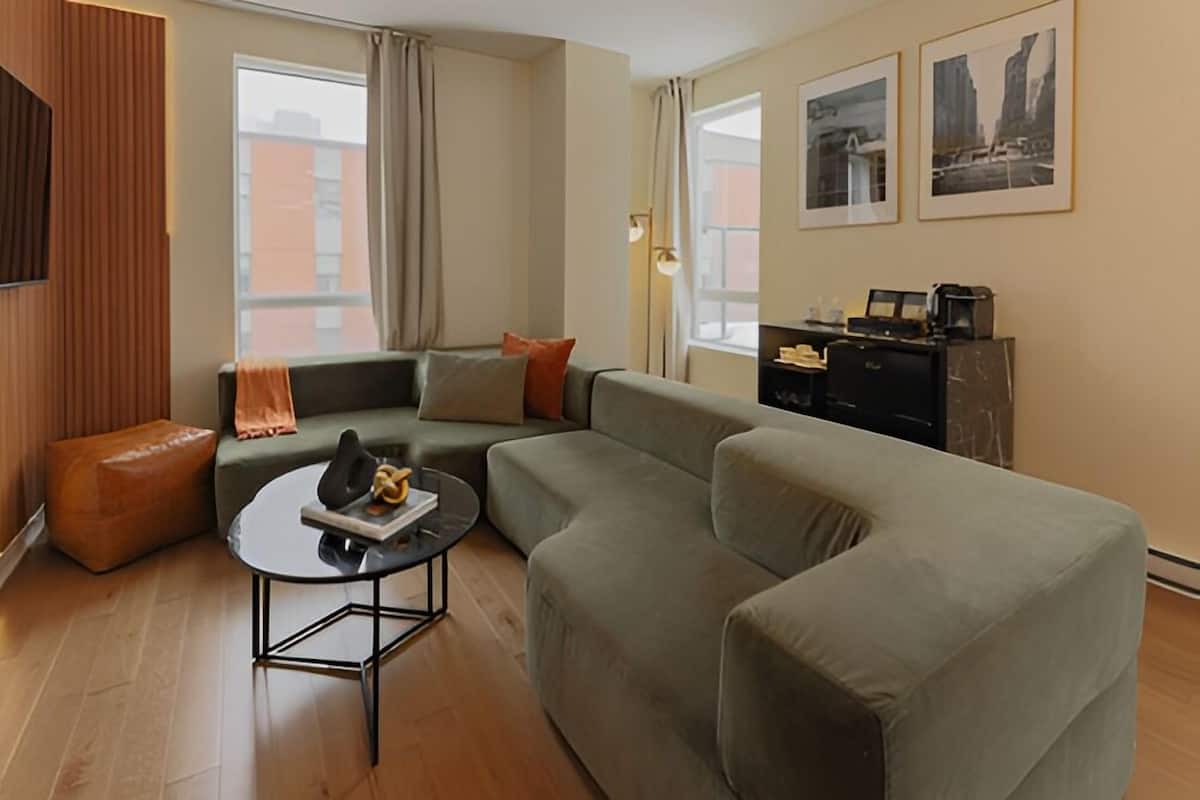 Un salon moderne avec un canapé d’angle, une table basse ronde et un téléviseur à écran plat fixé au mur.