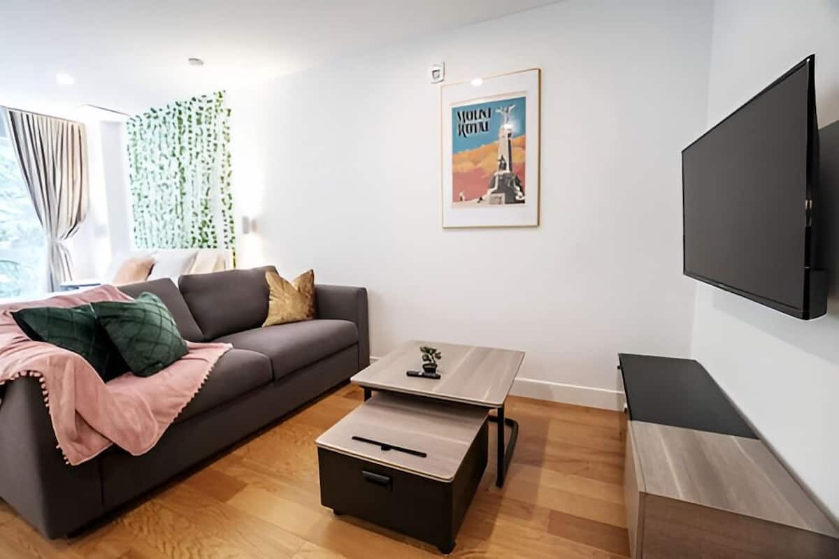 Un salon moderne avec un canapé, une table basse, un téléviseur et un tableau encadré accroché au mur.