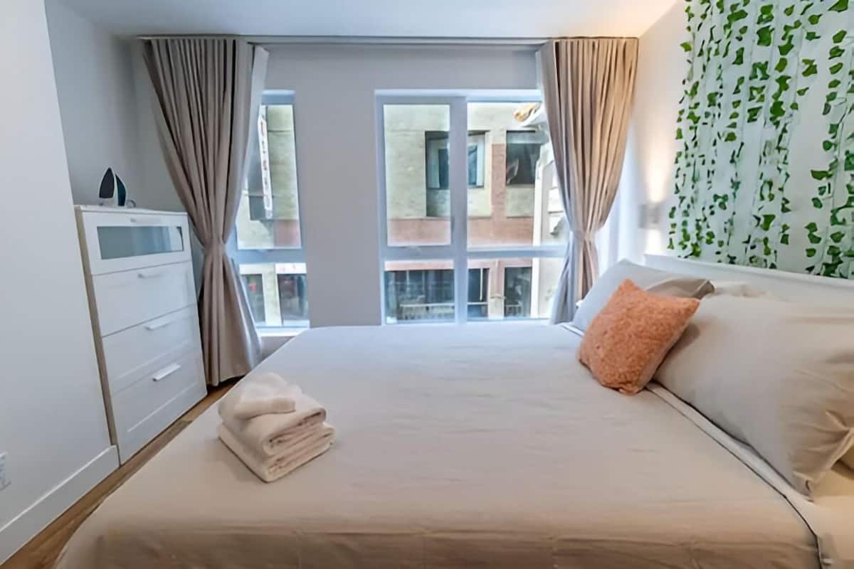 Une chambre à coucher avec un lit, une commode et une fenêtre avec des rideaux.