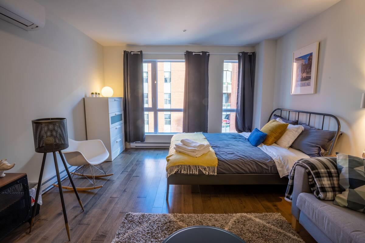 Une chambre moderne avec un lit, un bureau, une chaise et une fenêtre avec des rideaux.