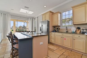 Una cocina moderna con una isla central, armarios color beige y un ventanal que proporciona luz natural.