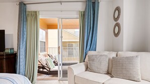 A room with a white sofa, a bed with striped bedding, and a balcony with a chair and a table. - Last Minute Disney Getaway! Townhouse with Private Pool. Book Now! #87733 (Orlando)