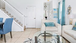 A living room with a staircase, a glass coffee table, and a beige sofa. - Last Minute Disney Getaway! Townhouse with Private Pool. Book Now! #87733 (Orlando)